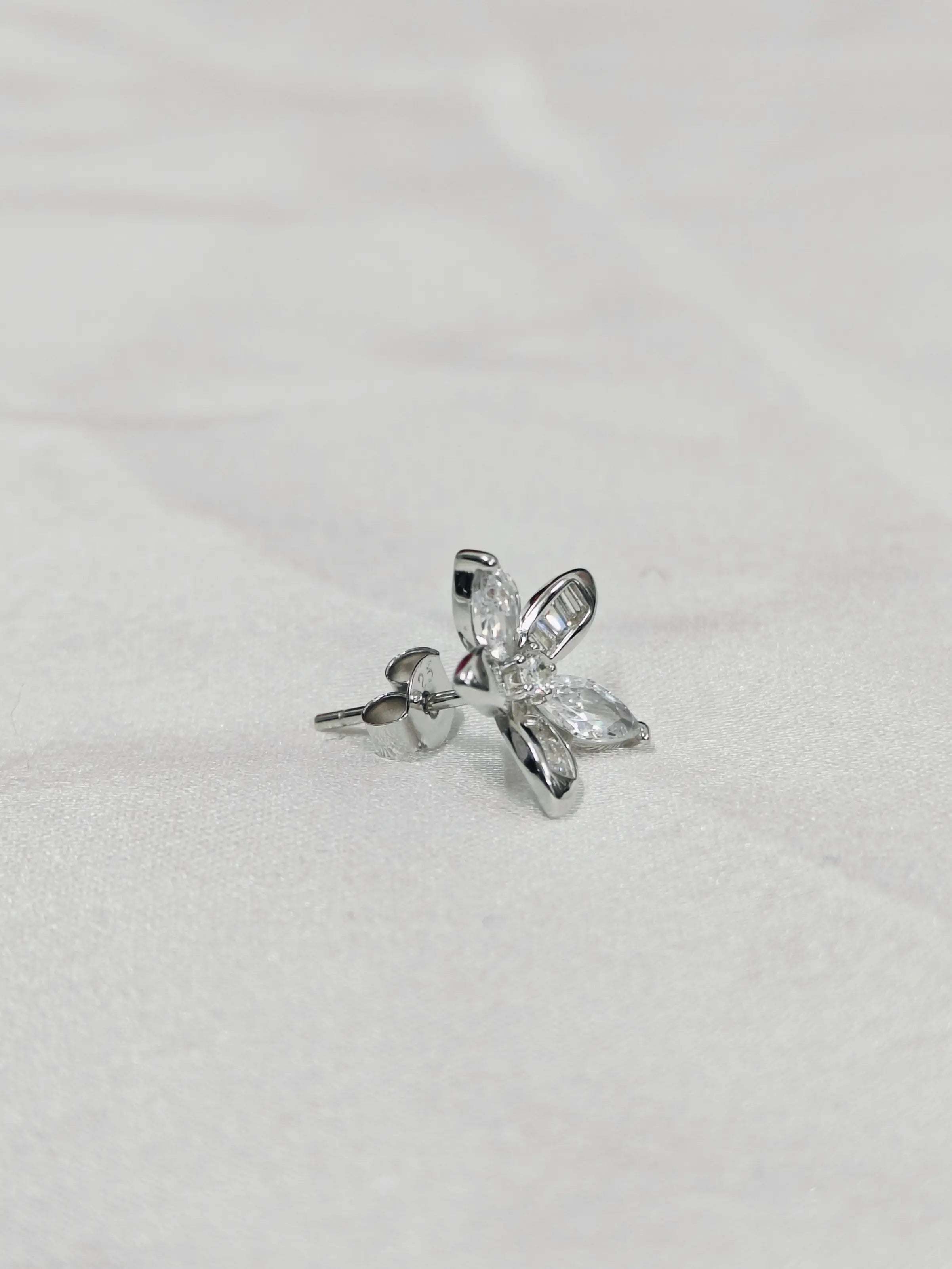 Silver butterfly-shaped earring on a light gray background